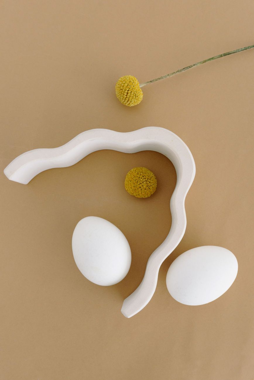 A composed shelf with ceramic vessels, a folded linen throw, and carefully placed objects